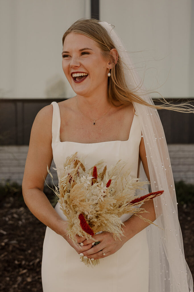 bride holding boho pampas bridal bouquet and smiling