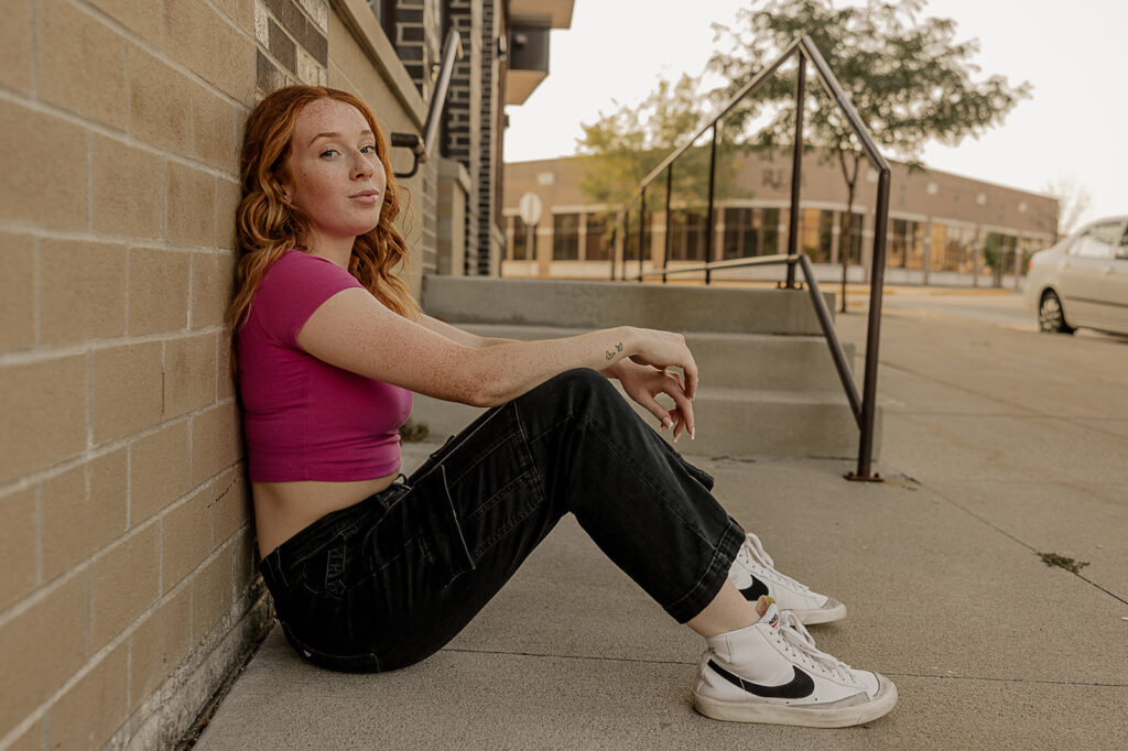 senior leaning up against brick wall for photoshoot