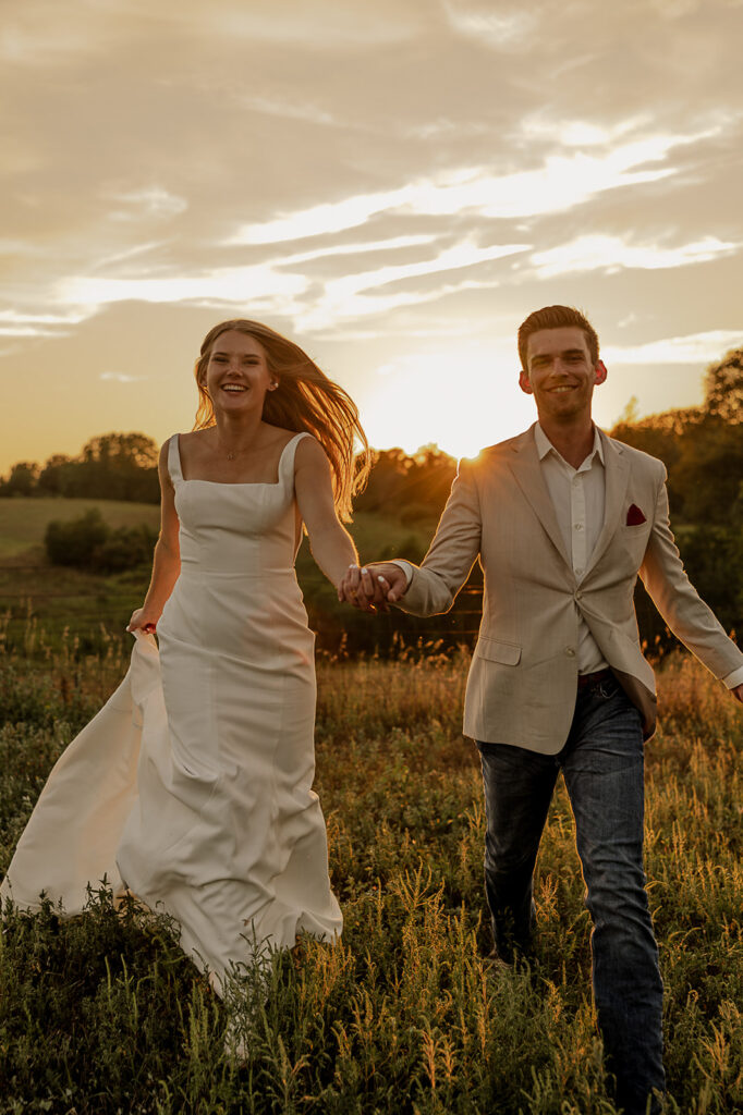 bride and groom holding hands and running in a field iowa wedding photographer