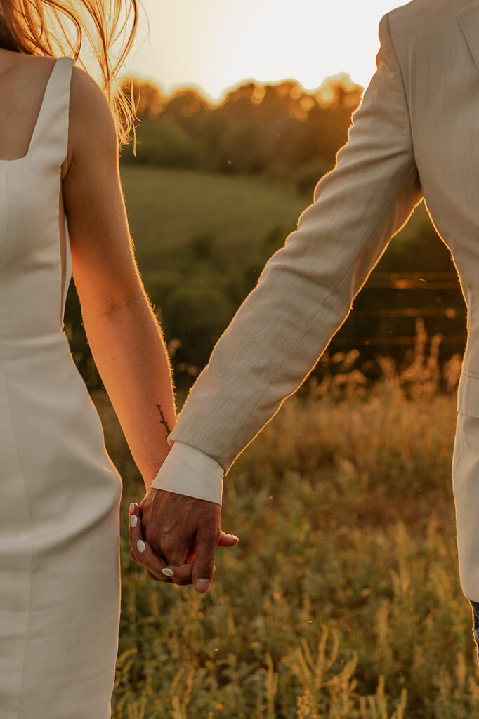 bride and groom holding hands and running in a field iowa wedding photographer