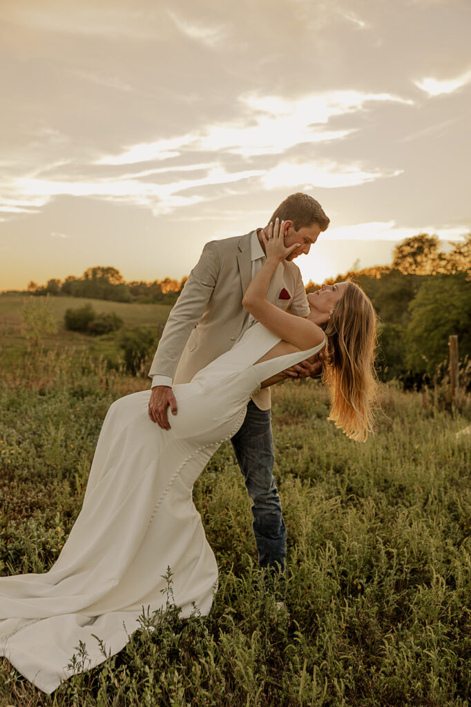 bride and groom standing in a field during sunset portraits iowa wedding photographer