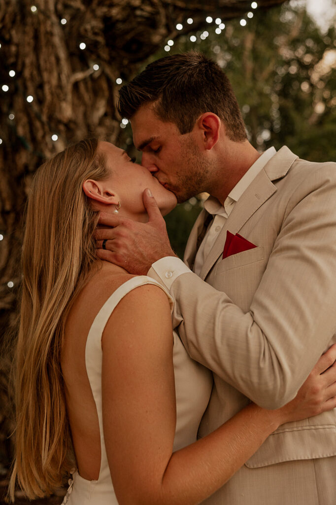 bride and groom kissing during reception with cafe lights in background