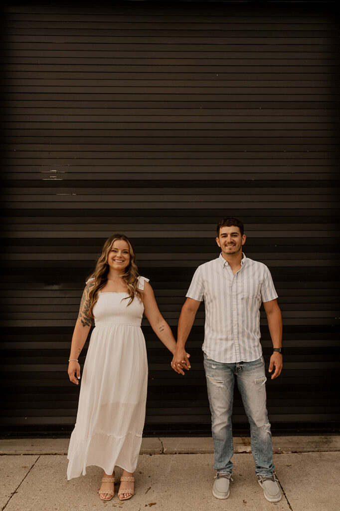 couple standing and smiling in front of building