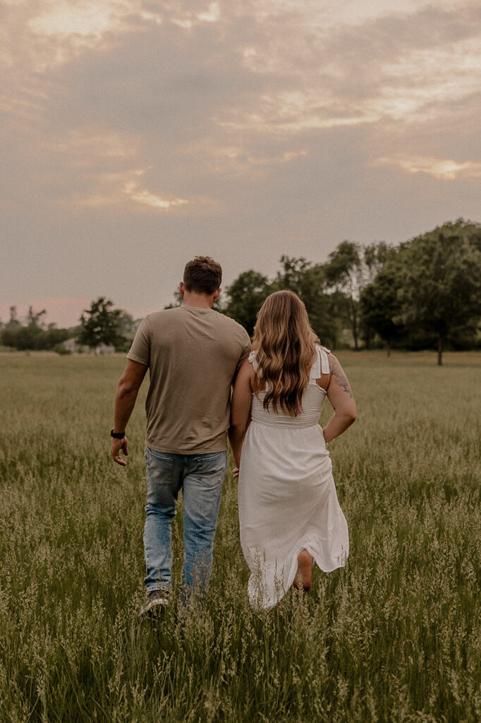 couple walking in field during golden hour