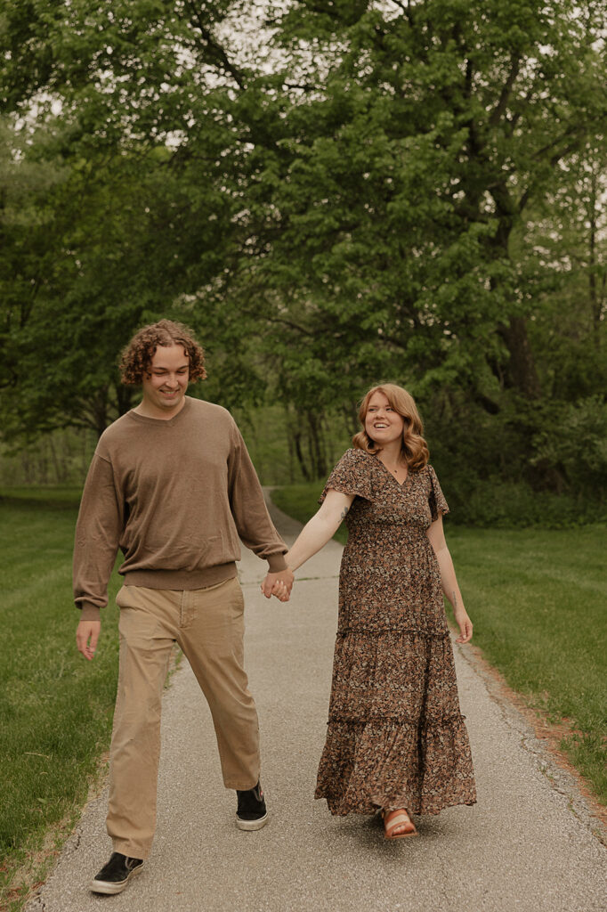 couple holding hands and walking on a trail for engagement session