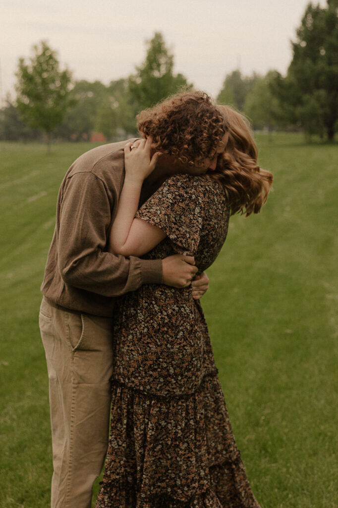 couple laughing and hugging in a field