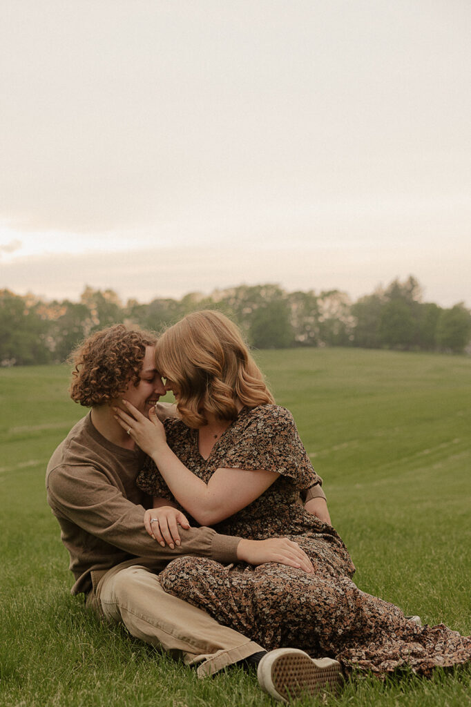 couple sitting in a field in iowa during engagement session