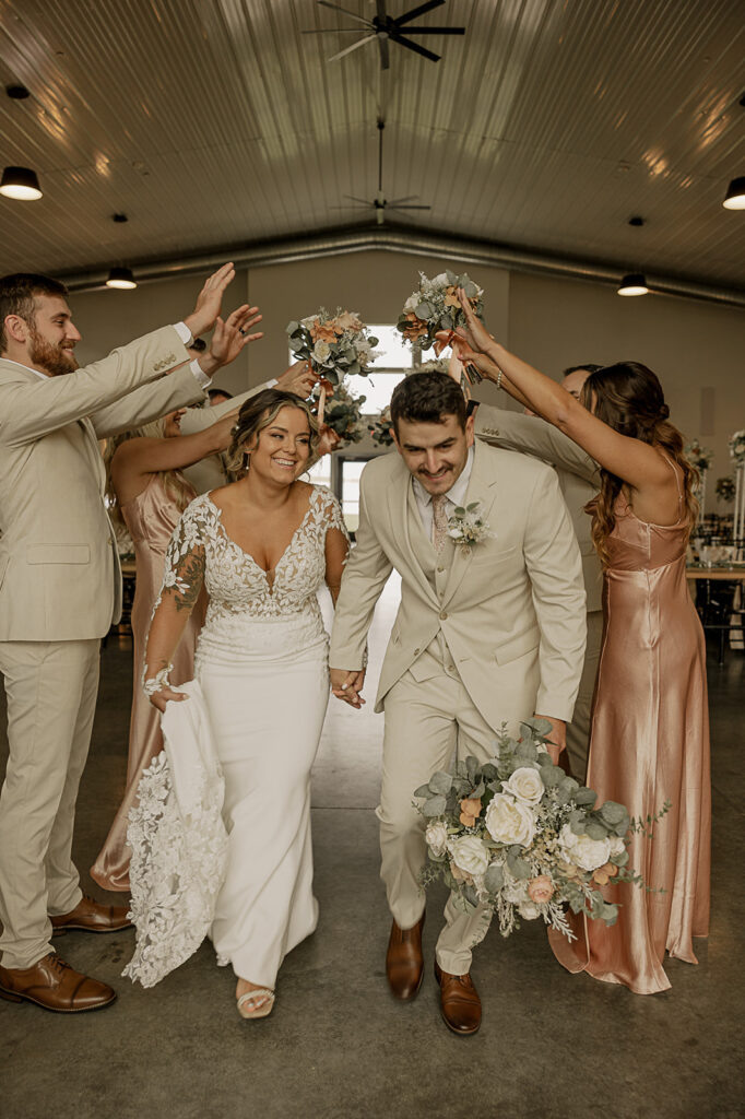 bridal party tunnel photos bride and groom walking and smiling