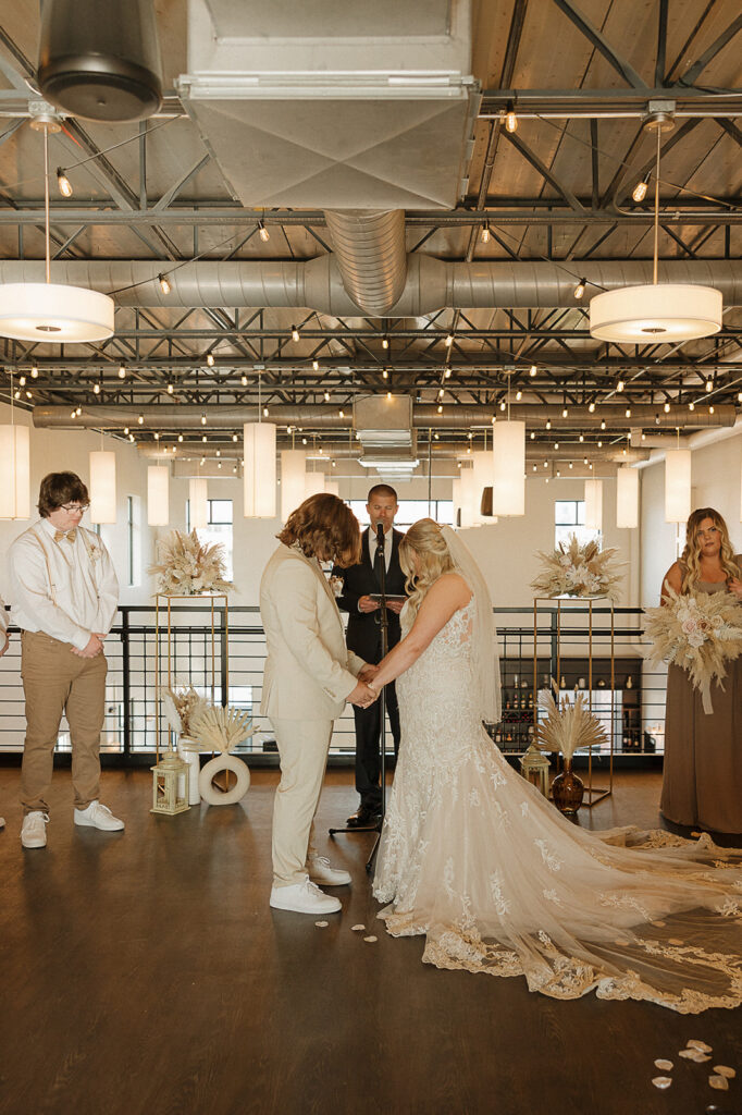 indoor wedding ceremony bride and groom praying in the district venue