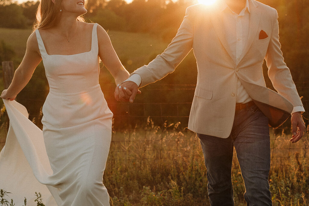 bride and groom holding hands and running during sunset