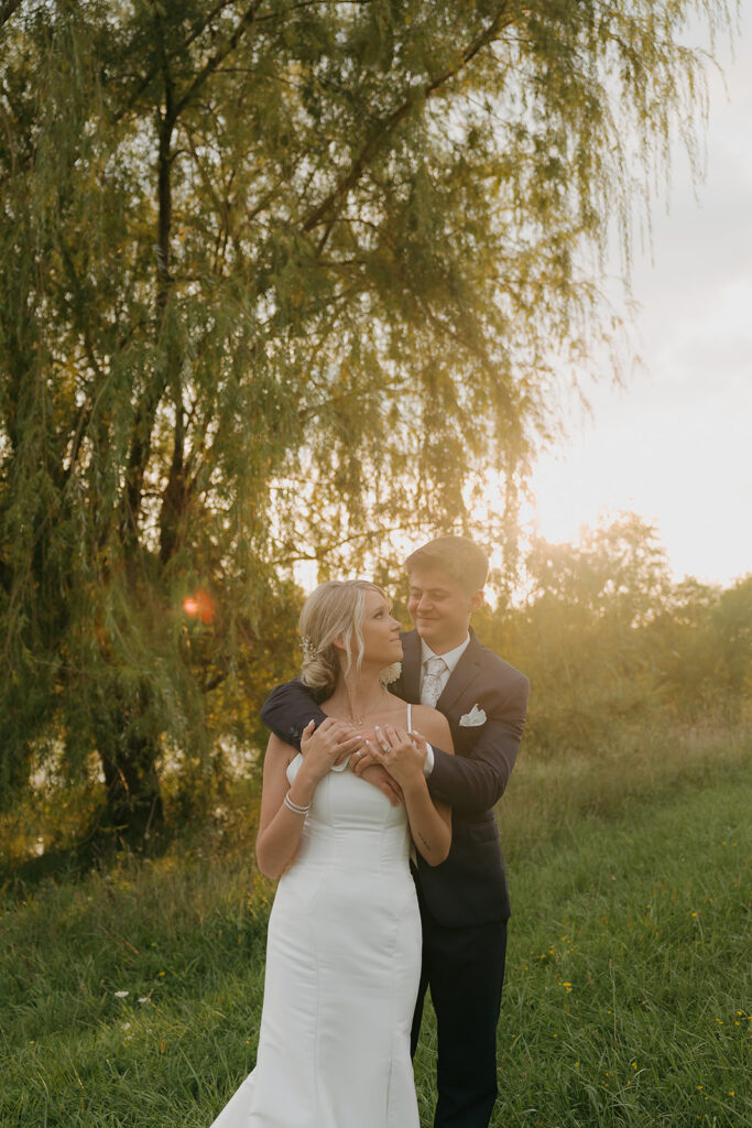 couple photos in front of willow tree during sunset after wedding ceremony