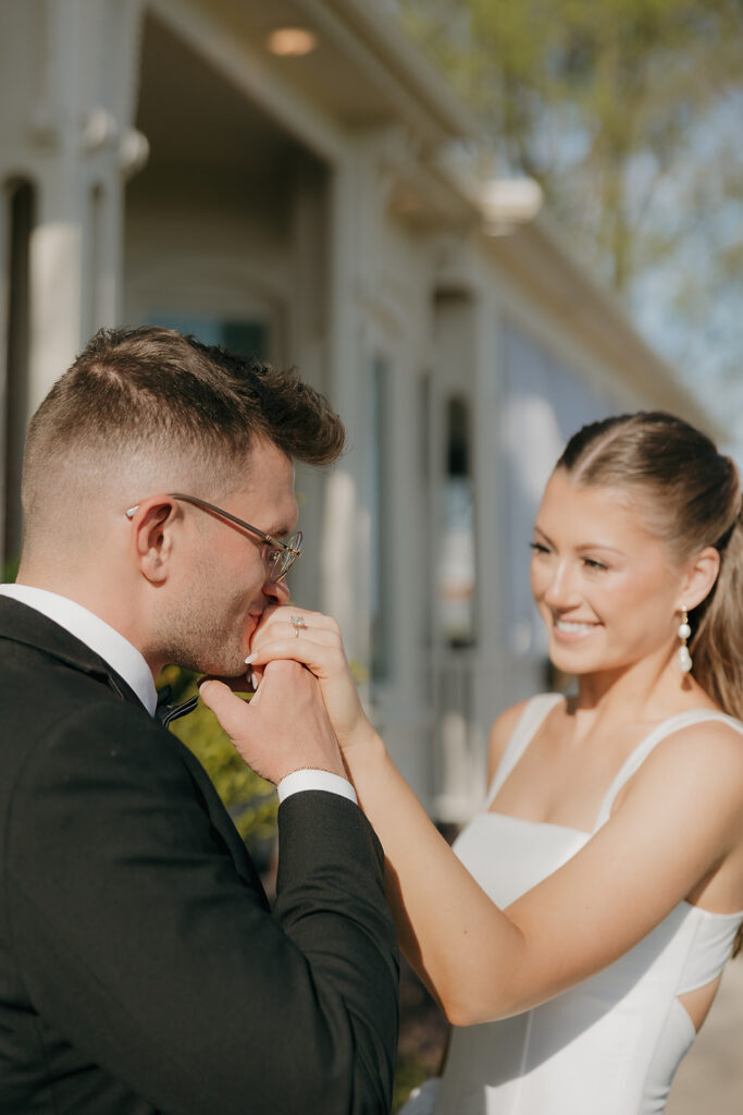 groom kissing the back of bride's hand