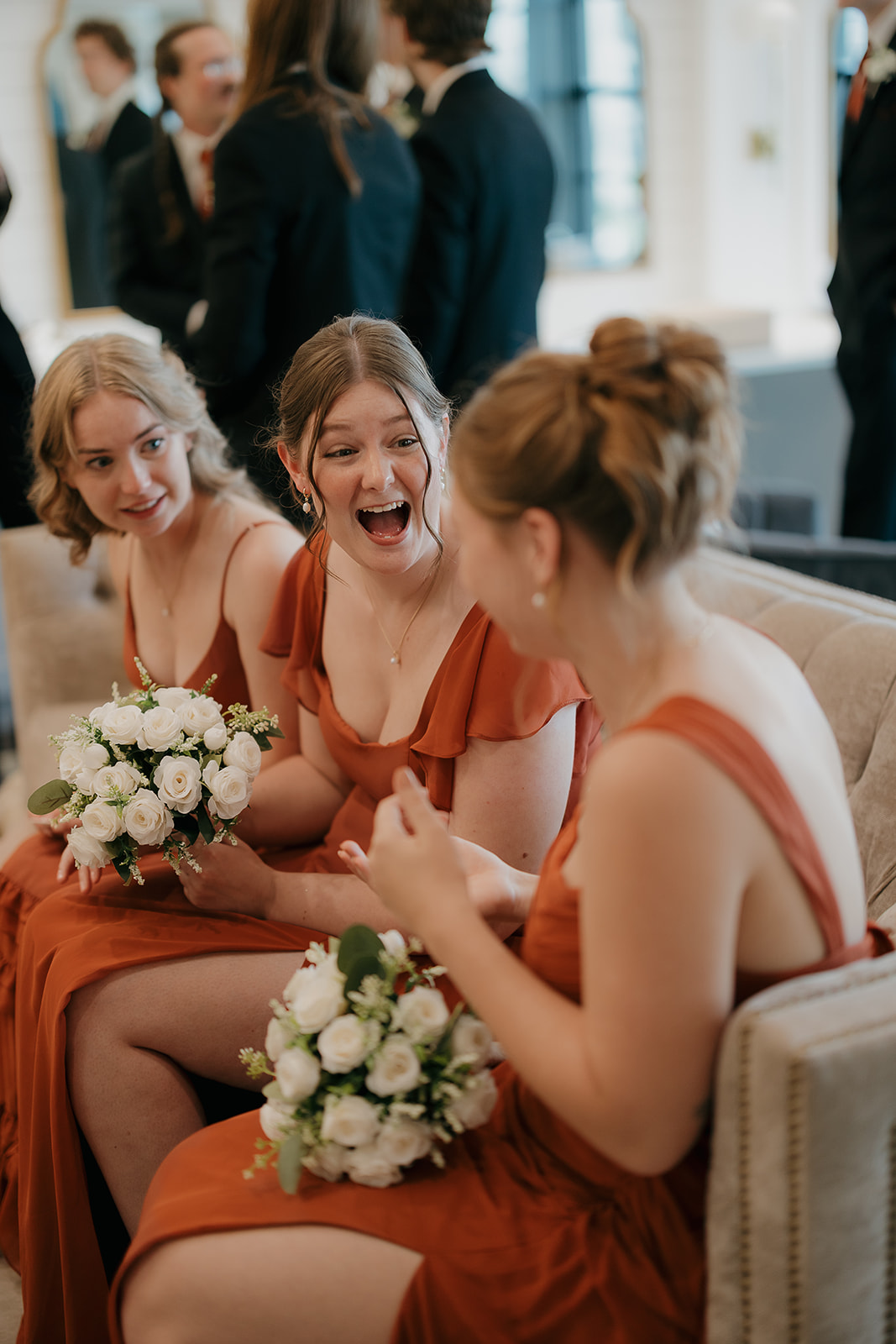 Bridesmaids laughing together on a couch before the ceremony