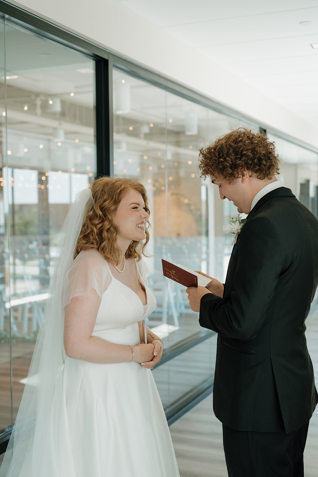 Bride smiling while listening to the groom read his vows, a heartfelt moment shown through documentary wedding photography