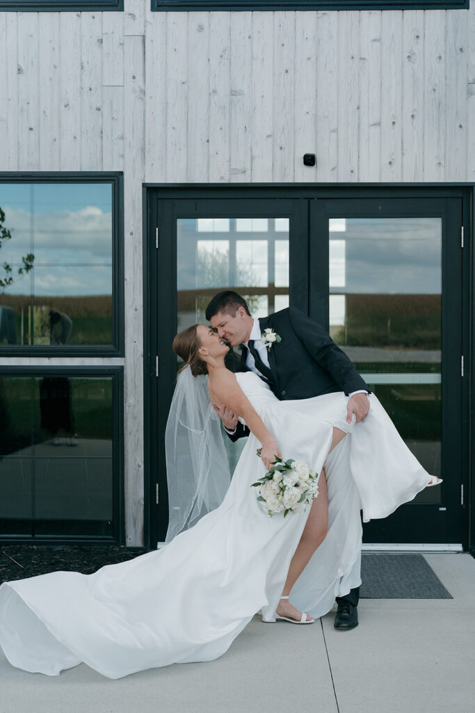 The groom dipping the bride as she holds her wedding bouquet