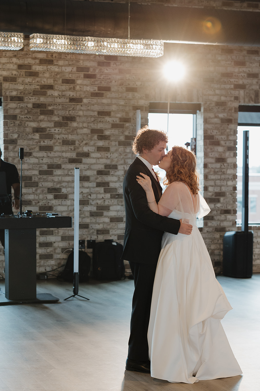 Bride and groom sharing a kiss during their first dance, beautifully framed through documentary wedding photography
