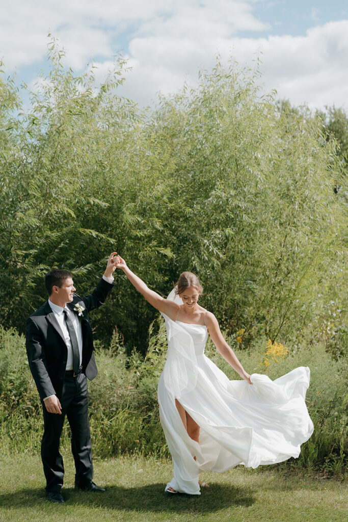 The bride and groom smiling and dancing together on the lawn at their outdoor wedding venue in Iowa.