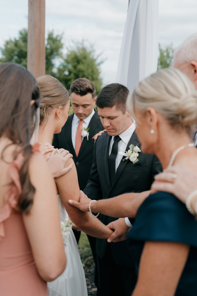 The wedding guests huddled around the bride and groom to pray over them during the ceremony