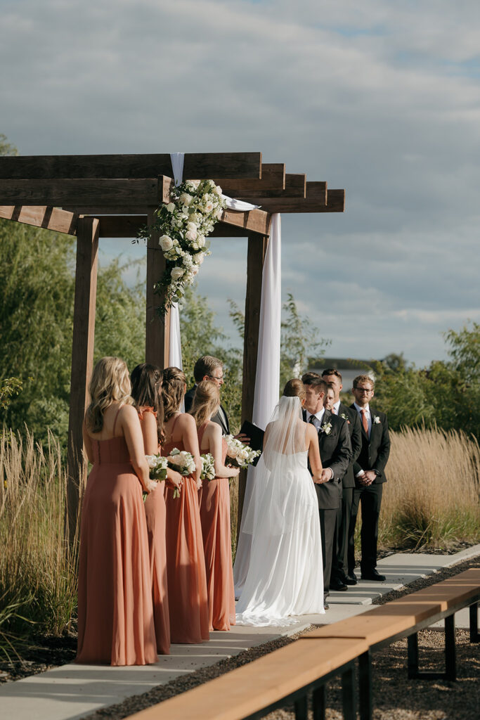 A detail photo of the wedding party and bride and groom standing at the alter for their outdoor wedding in Iowa