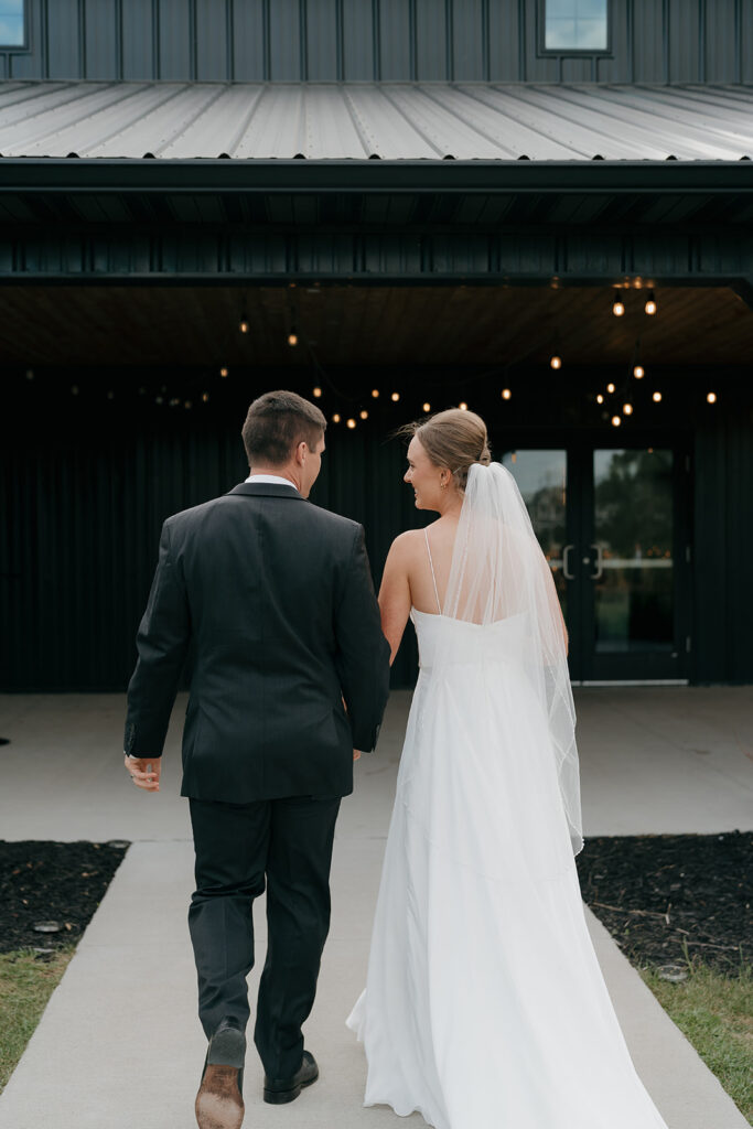 The bride and groom smiling and walking into their wedding reception