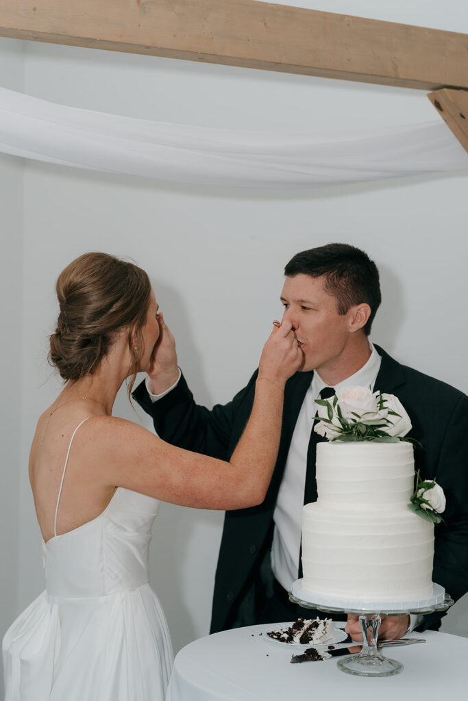 The bride and groom feeding each other a bite of their wedding cake.