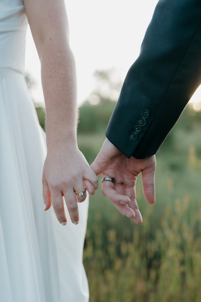 The bride and groom interlocking their pinkies at sunset for a detail shot during their bride and groom portraits.