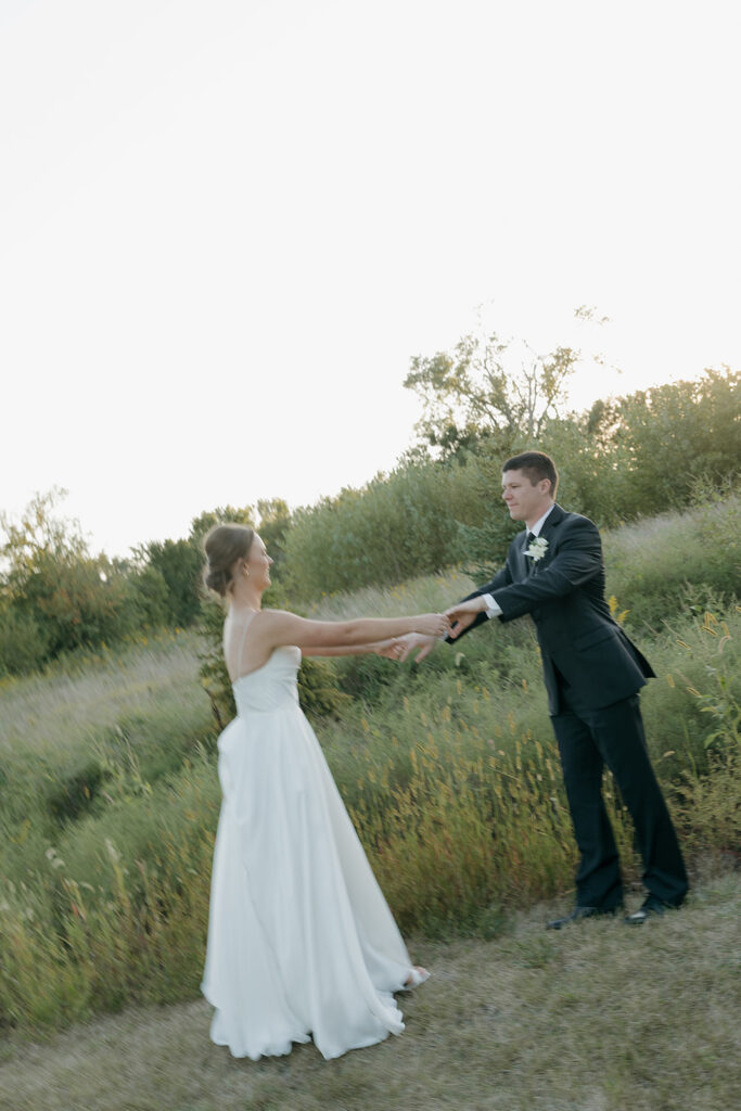 The bride and groom dancing in a field during golden hour at their outdoor wedding venue in Iowa