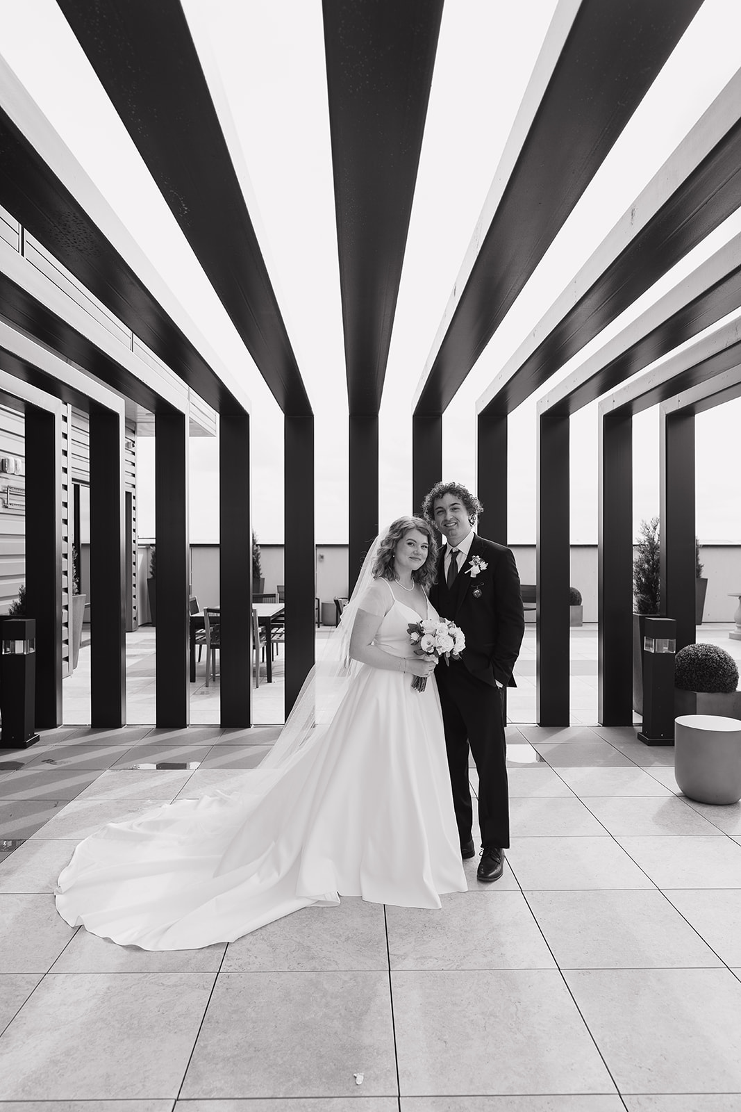 Black and white photo of the bride and groom standing outside their wedding venue for some documentary wedding photography portraits.