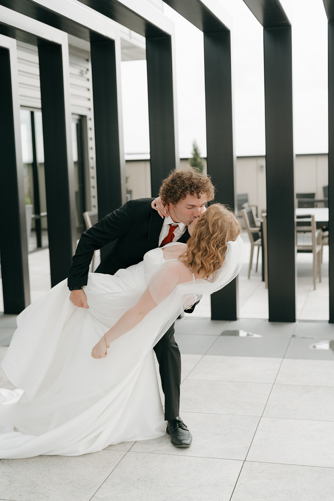 The groom dipping the bride outside and kissing her during their bride and groom portraits.