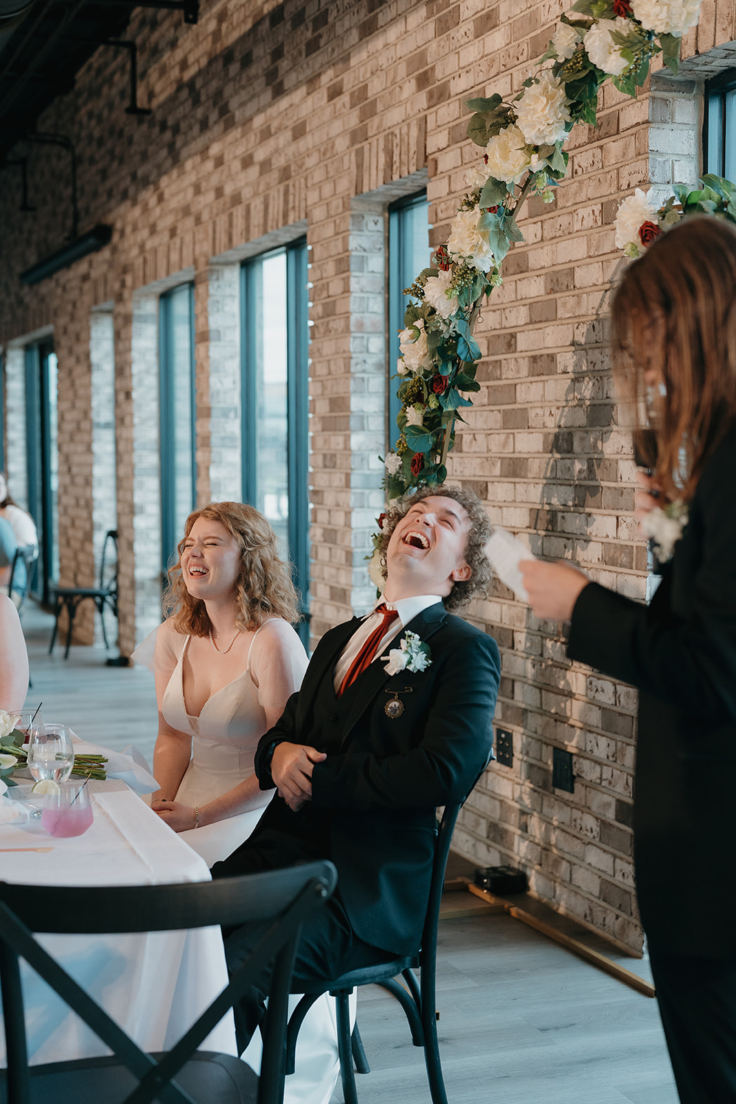 Bride and groom cracking up during reception toasts, a perfect candid moment that reflects documentary wedding photography