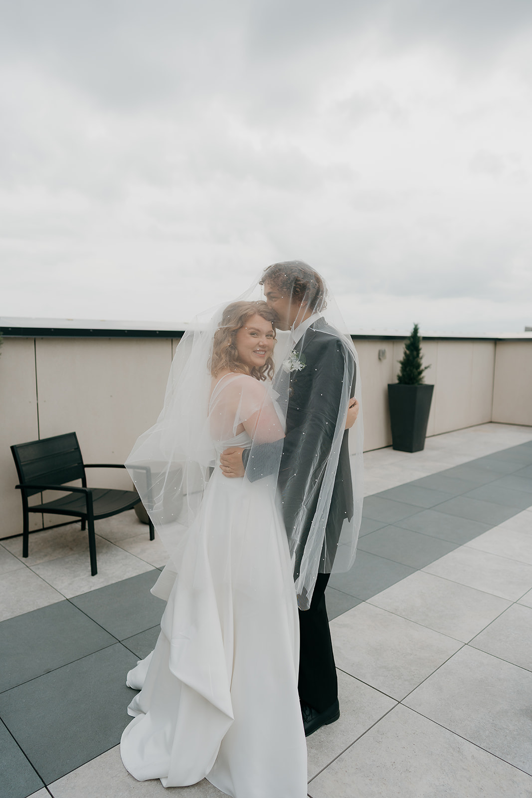 A editorial bride and groom portrait of the groom kissing the bride's forhead under her veil.