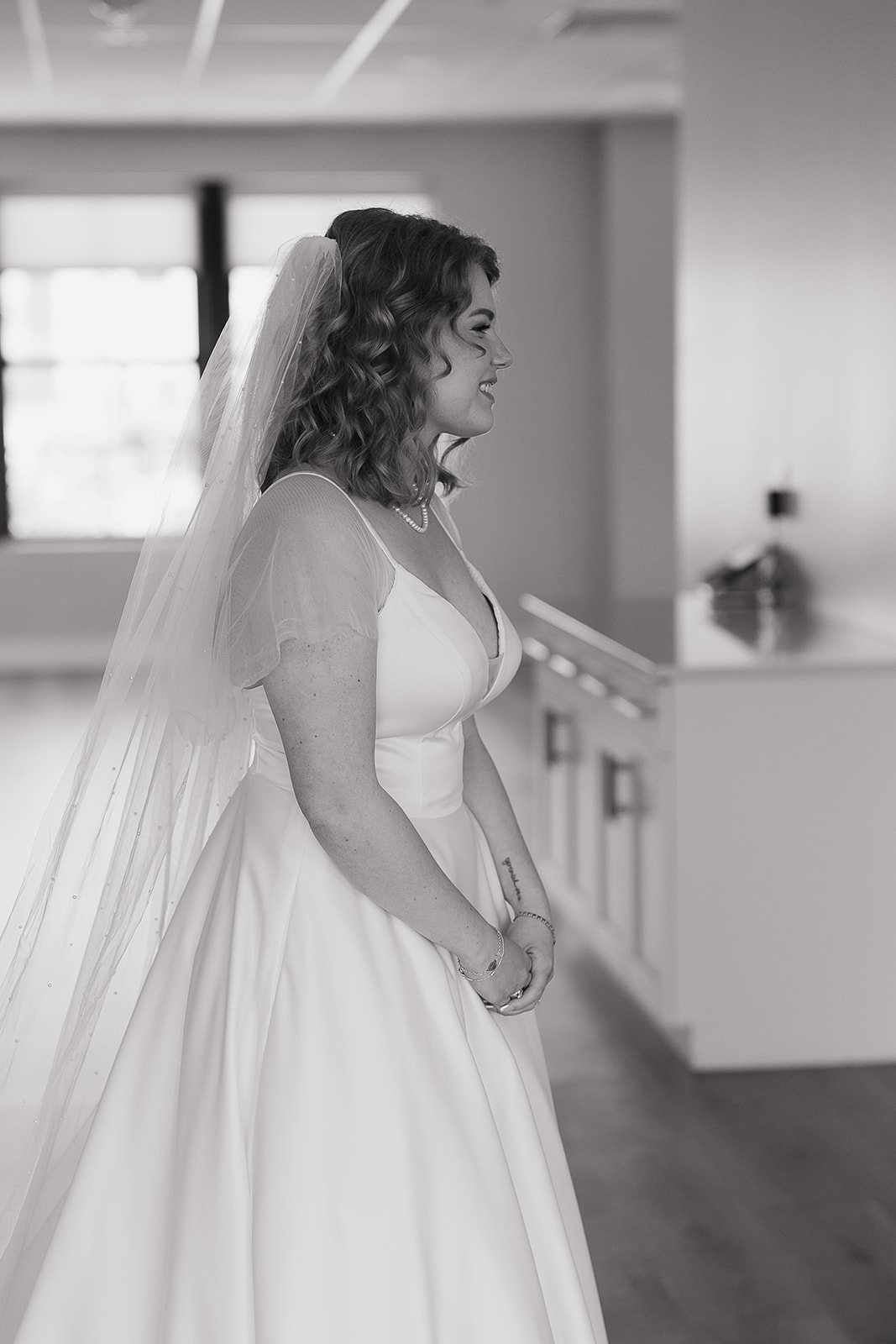 A black and white photo of a bride in her dress doing a first look with her bridesmaids.