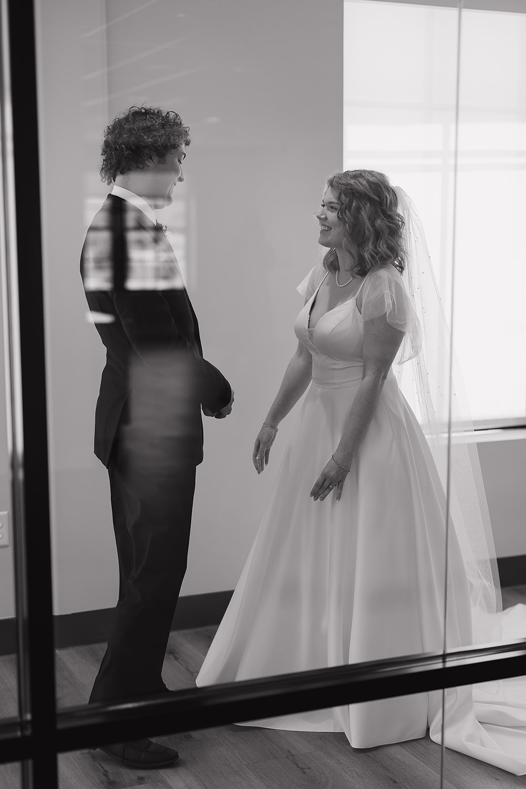 The bride and groom doing a first look together in a hallway. Captured by a Des Moines Wedding Photographer