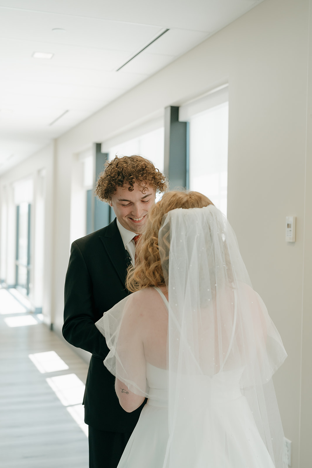 The groom smiling down at his vow book as he reads his vows to the bride. Captured by a Des Moines Wedding Photographer