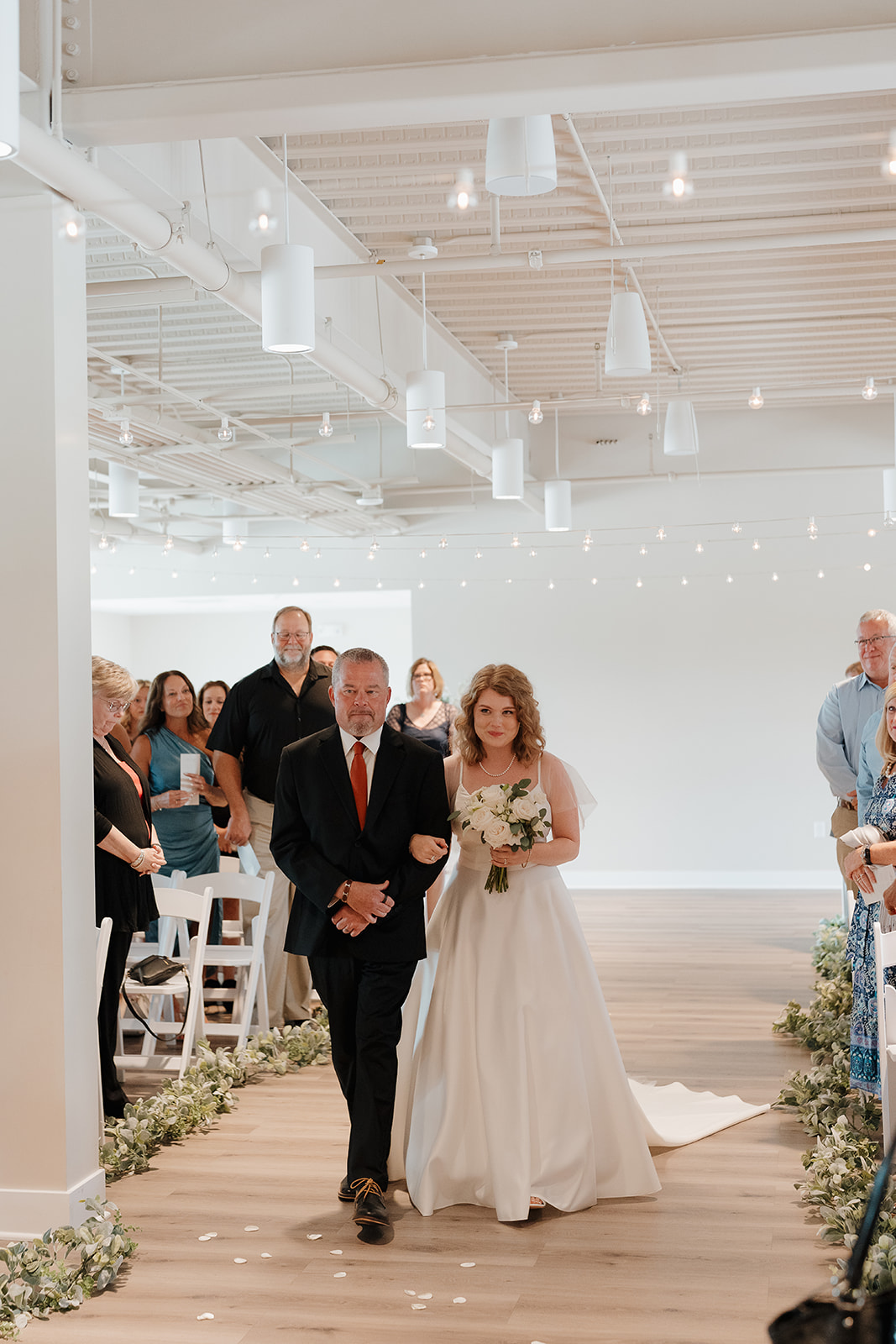 The bride's dad walking her down the aisle during the wedding ceremony. Captured by a Des Moines Wedding Photographer
