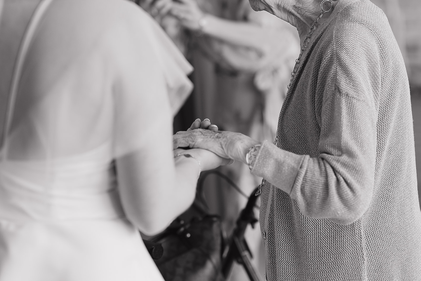 The bride holding her grandma's hand for an intimate black and white photo shot. Captured by a Des Moines Wedding Photographer