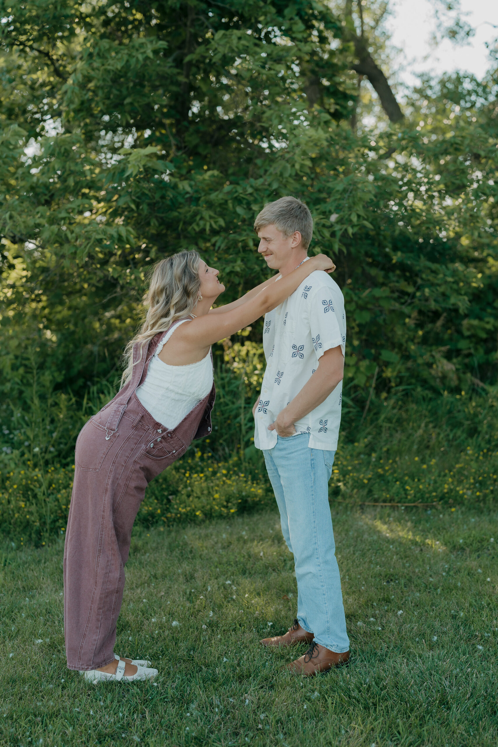 A couple taking maternity pictures with the mom leaning into the soon to be dad as they smile at each other.