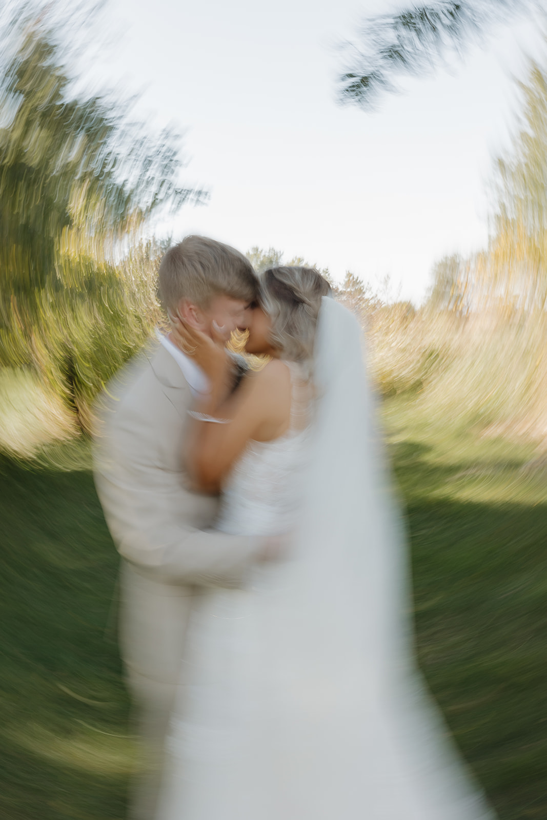 The bride and groom lean into each other laughing, framed closely to preserve a genuine, unposed moment.