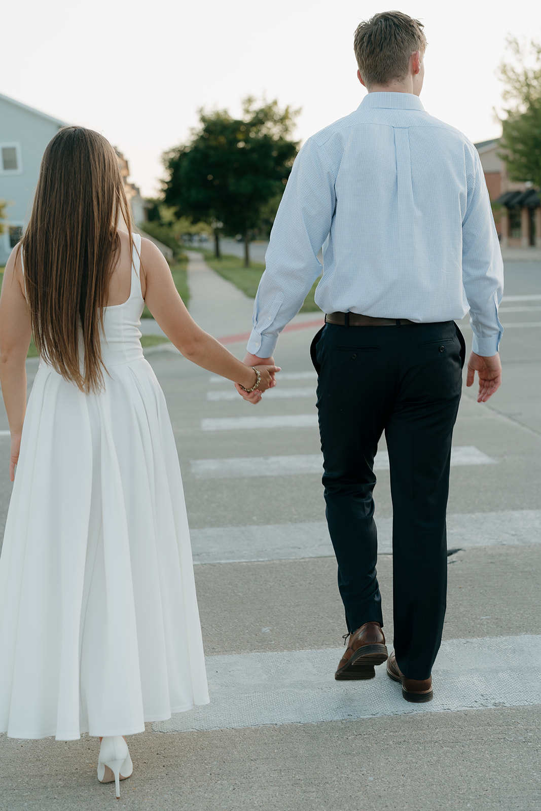Romantic sidewalk engagement portrait of a couple embracing outside a brick building, showcasing one of their favorite Unique Engagement Photo Locations.