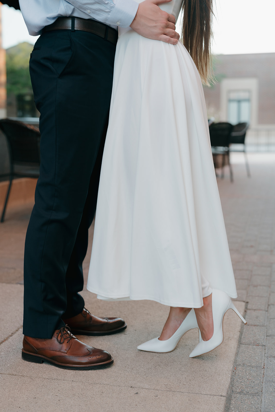 Romantic city engagement portrait of the couple embracing outside a restaurant patio, highlighting charm and character in Unique Engagement Photo Locations downtown.