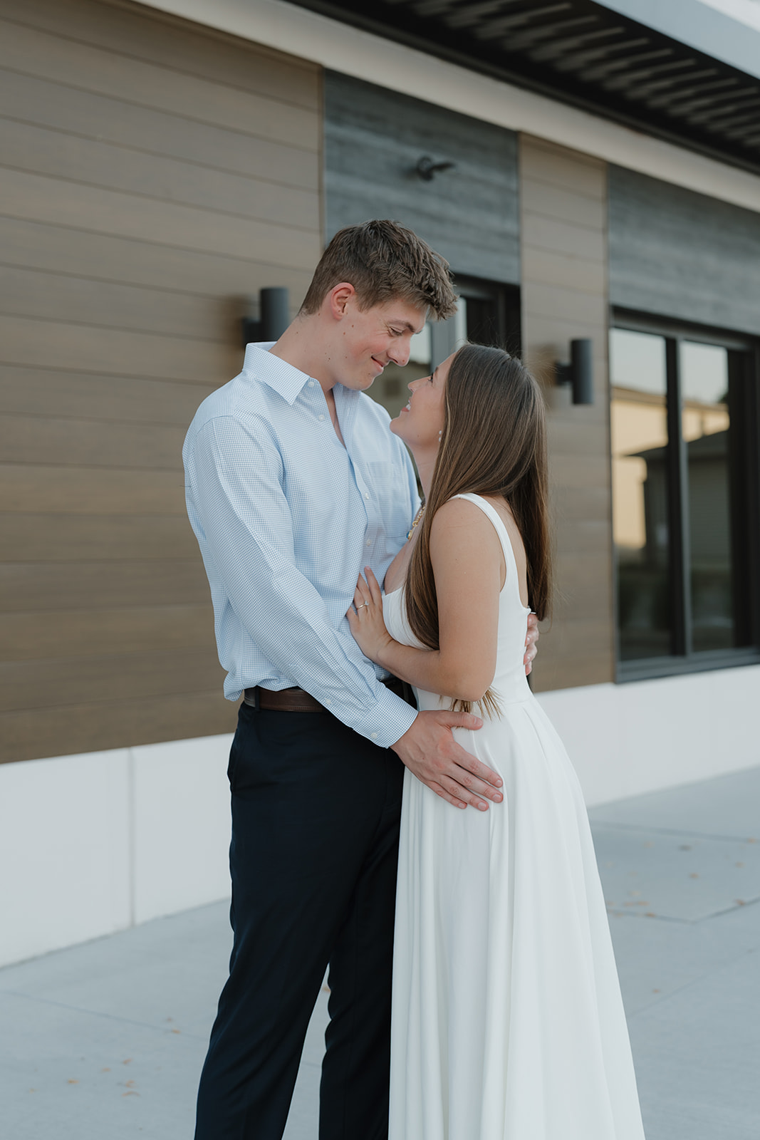 Stylish downtown engagement photo of a couple embracing against a modern architectural backdrop, showcasing an urban setting as one of the most Unique Engagement Photo Locations.