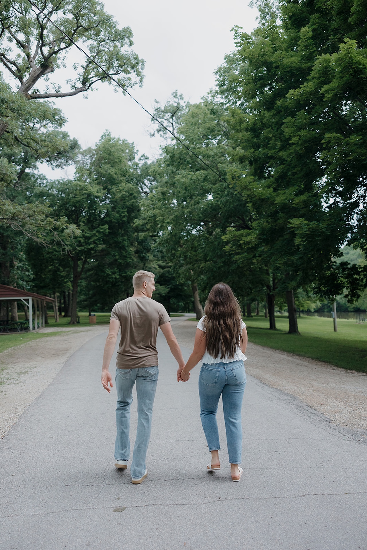 Knowing when to take engagement photos means capturing walks like this couple strolling hand in hand through a tree-lined park path