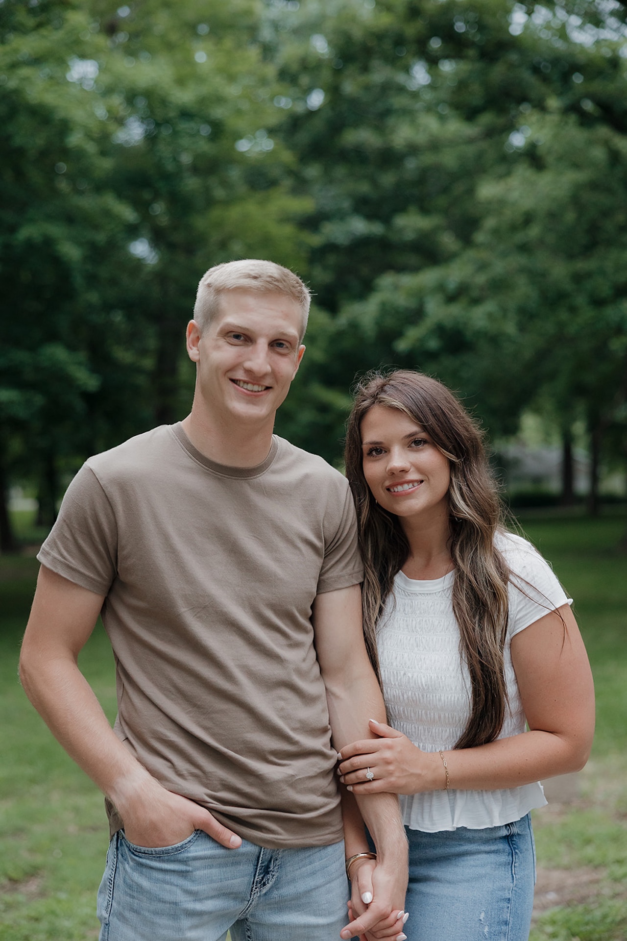 An engaged couple posing for a portrait in a green Iowa park, showing why summer is the best time for when to take engagement photos