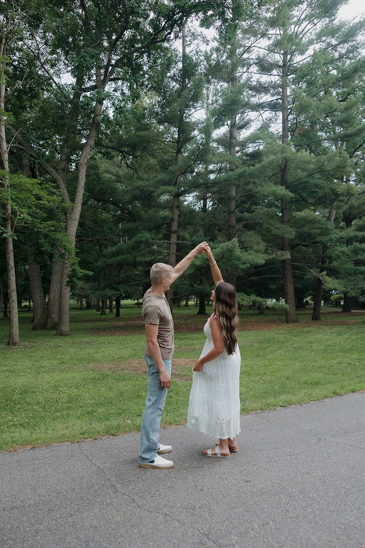 A dreamy motion-blur shot of an engaged couple sharing a kiss on a green lawn surrounded by trees
