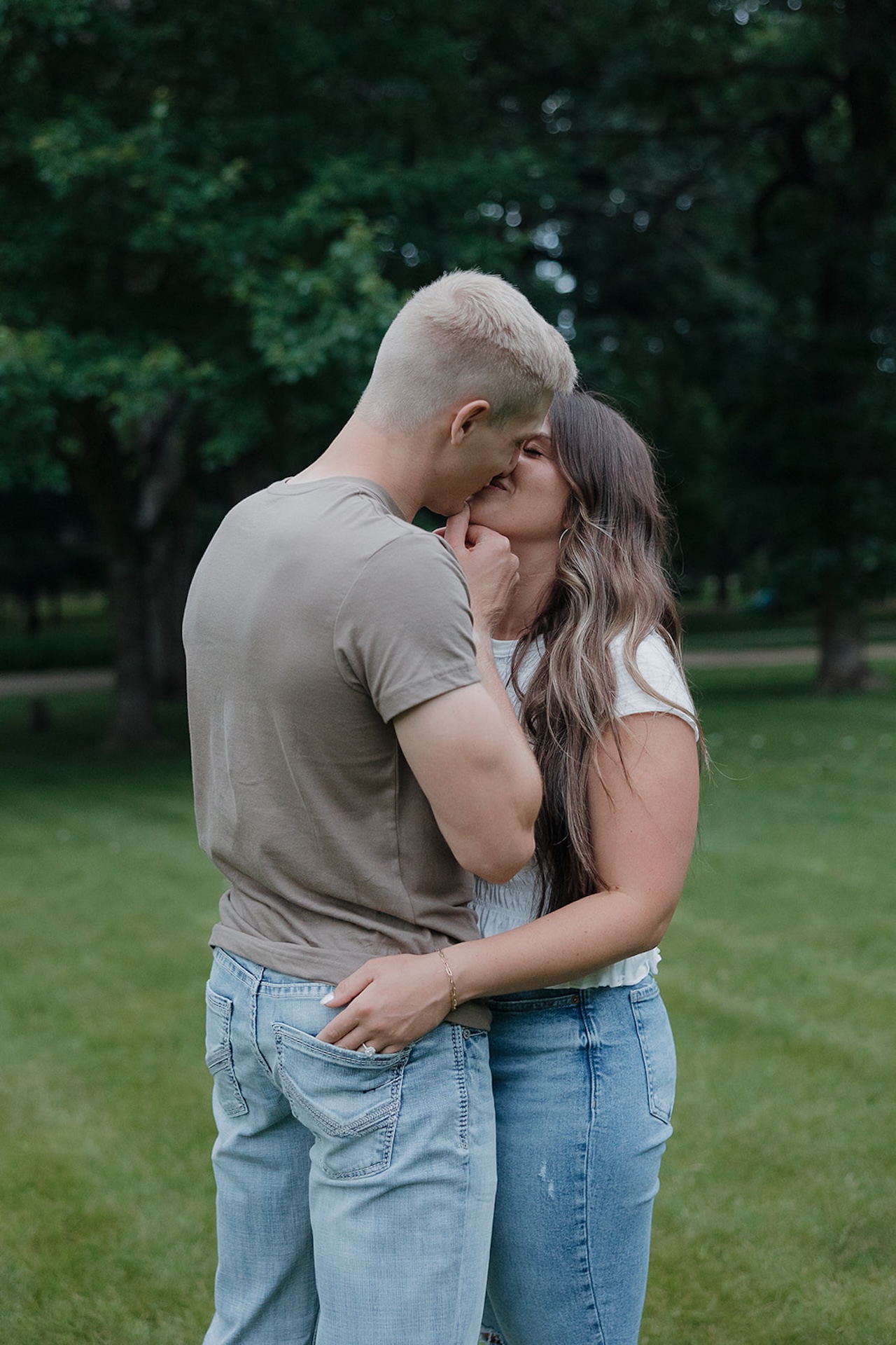 A couple sharing an intimate almost-kiss in a green Iowa park — everything about this moment shows why summer is the best time to take engagement photos