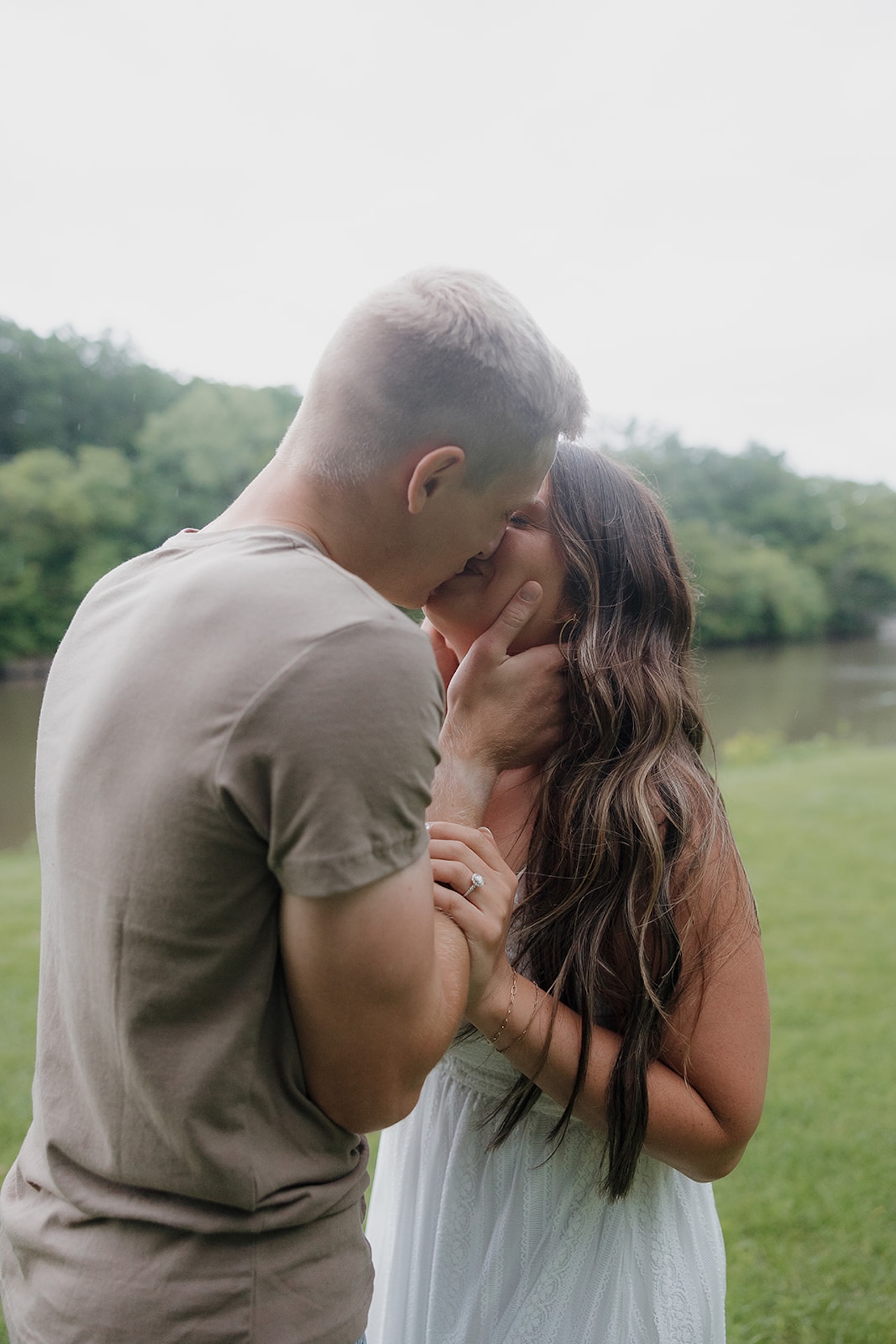 A couple sharing a tender kiss by a river during their summer engagement session in Iowa