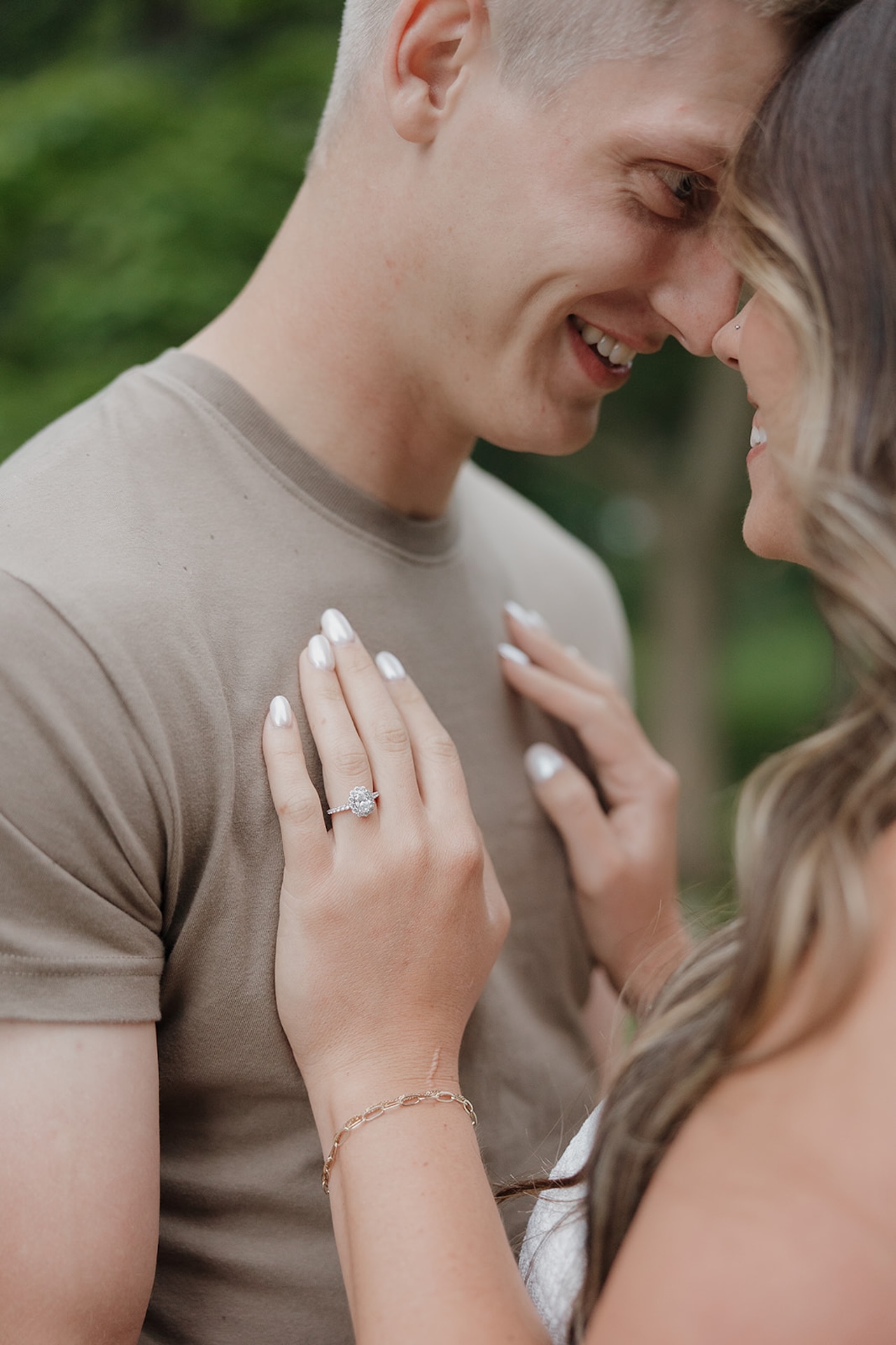 A joyful couple smiling nose-to-nose outdoors, with the engagement ring on display — a candid moment that shows when to take engagement photos