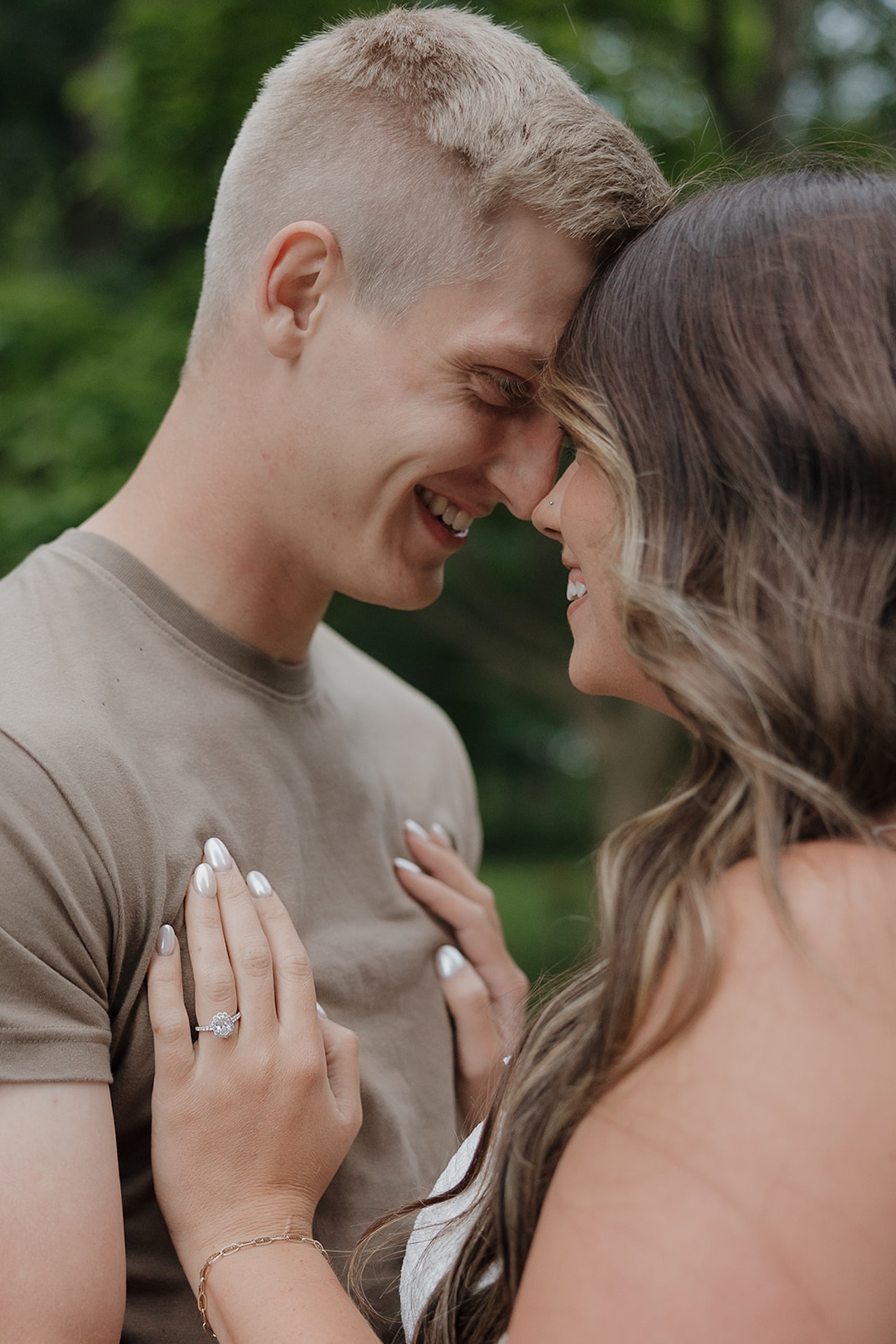A joyful couple smiling nose-to-nose outdoors, with the engagement ring on display — a candid moment that shows when to take engagement photos