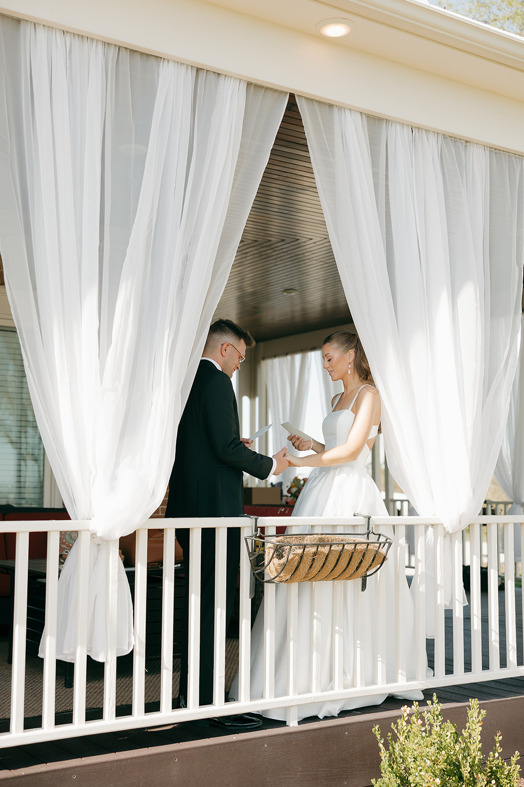 Bride and groom exchanging private vows on a draped porch, old money wedding vows
