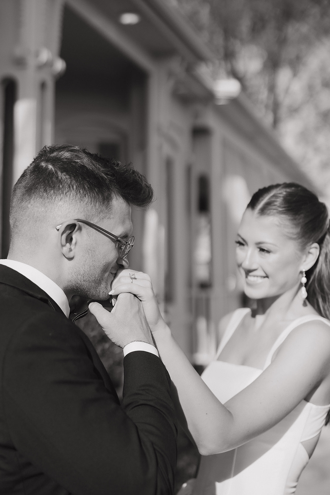 Groom kissing the bride's hand in black and white, one of those tender old money wedding moments that stops time
